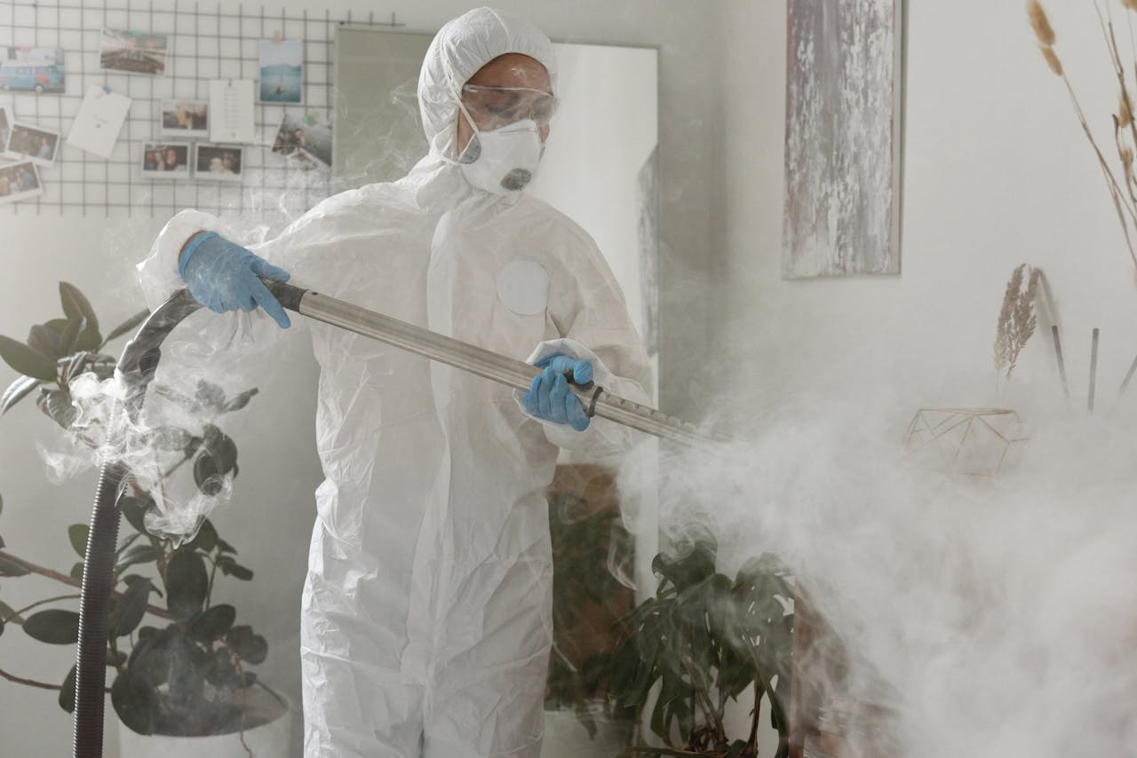 about-02 Person in PPE fumigating indoors for health safety during COVID-19.